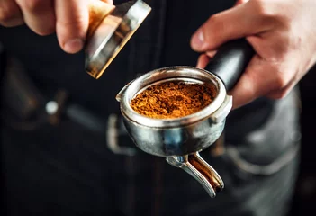 Foto auf Alu-Dibond Barista holding portafilter and coffee tamper making an espresso coffee. © Dmytro Panchenko