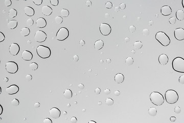 Rain drops on window glasses surface with cloudy background .