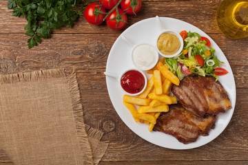 Grilled pork neck served with French fries and salad.