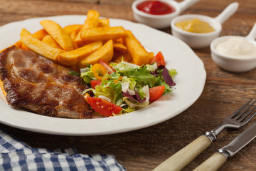 Grilled pork neck served with French fries and salad.