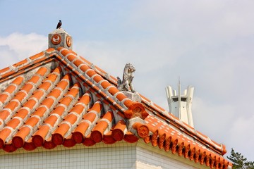 赤瓦の屋根の上のシーサーと鳥