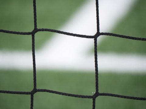 Goal a soccer net with green grass field. Detail of bound strings