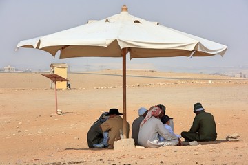 砂漠のパラソルの下で休憩する人たち