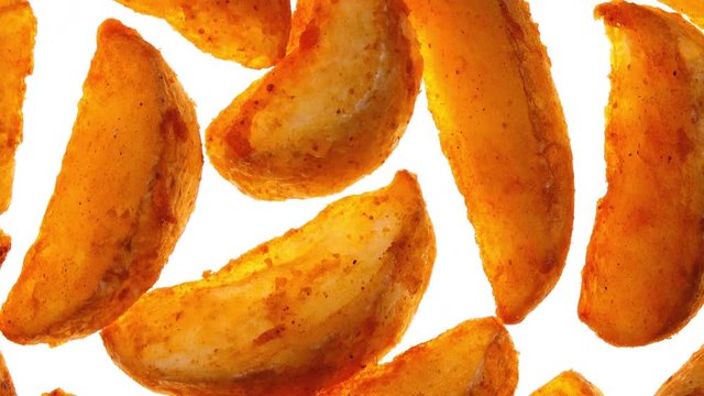 Vivid closeup flatlay view of fried potato wedges rotating on white background in 4K. Popular fast food.
