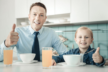 Being satisfied. Cheerful girl expressing positivity while eating and raising thumb