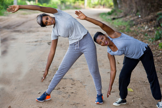 Two beautiful women doing stretching exercise in the park.