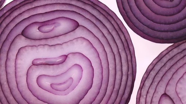 Sliced red onion rings rotating on white in 4K. Extreme closeup flatlay view of healthy food background with vegetable of rich vitamin.
