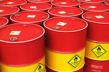 Group of rows of red stacked oil drums in storage warehouse