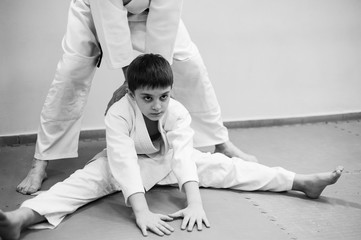 A boy in a kimono has an aikido training with a coach