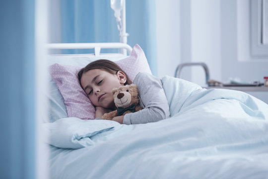 Sick girl sleeping with teddy bear in the hospital