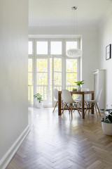 White chair at wooden table in spacious dining room interior with window. Real photo