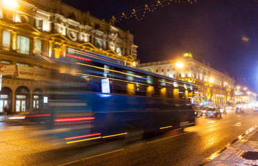 Fototapeta na wymiar Movement of a blurred blue bus on the avenue at night.