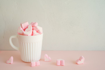 Fluffy pink heart marshmallow in vintage cup on white background with copy space