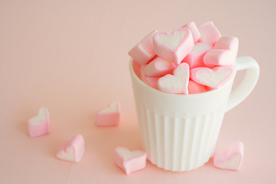 Fluffy pink heart marshmallow in vintage cup on pink background