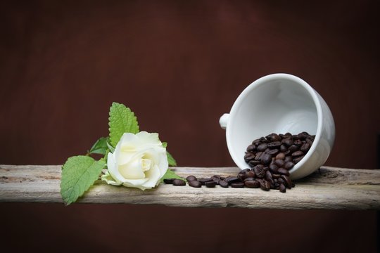 Kaffeebohnen und weiße Rose auf einem Holzbrett