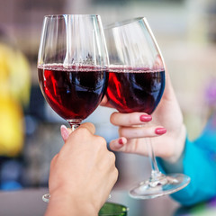 Glasses of red wine in their hands. Toast. Square. The concept of party