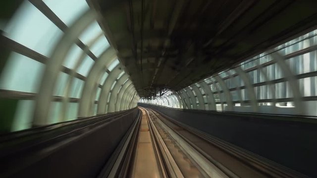 Train moves along metro or subway railroad half-open tunnel and passes by Hong Kong city buildings and skyscrapers. Electric rapid public transport, urban mass transit railway system or MTR.