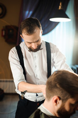 Master cuts hair and beard of men in the barbershop