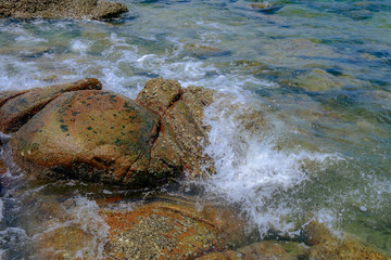 Sea wave with rock at sand beach with high speed shutter.