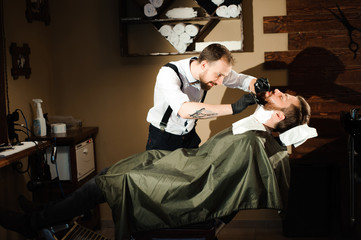 Master cuts hair and beard of men in the barbershop