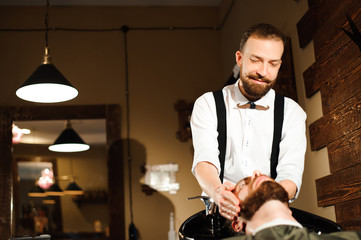 Master cuts hair and beard of men in the barbershop