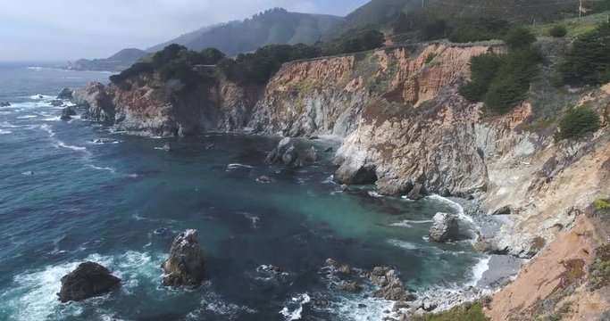 Flight over of rocky coastline. Ocean shore, waves crashing cliffs, California