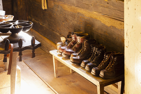 View into a small traditional shoemaker workshop with craft tools, equipment, materials and finished pairs of heavy leather shoes