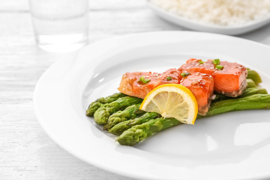 Fish fillet served with lemon slice and asparagus sticks on plate