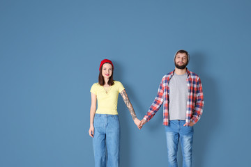 Trendy hipster couple posing together against color background