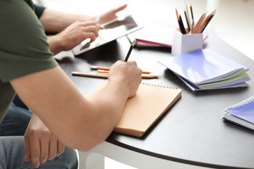 Male student doing homework at table, closeup