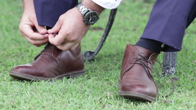 Close up of groom tying shoes