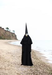 Strange figure in black cloak with the mirror face in seaside.