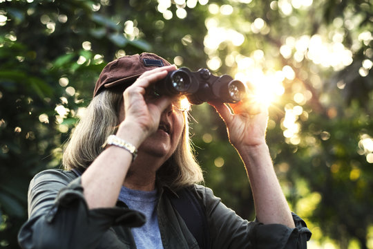 Elderly woman watching birds with binoculars