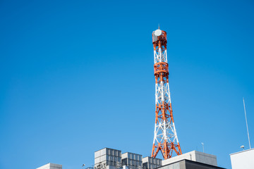 Communications Tower on the top of building with blue sky sunny day background.