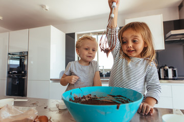 Kids preparing cake batter in kitchen