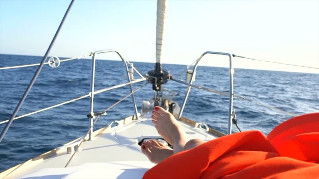 Beautiful Woman's Legs in the Bow of the Sailing Yacht. Sailing Boat with Deep Blue Sea and Clear Sky. Shot on RED Epic 4K UHD Camera.