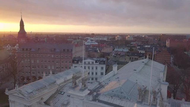 Drone shot flying up over Lund city and Lund University building. Aerial view of cityscape skyline at sunset