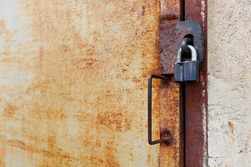 old rusty iron door with padlock and handle, side view close-up