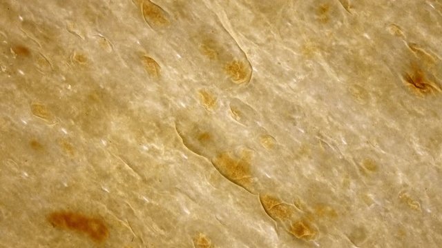 Thing tasty flat bread (lavash, pita, chapati, scone) rotating in 4K. Closeup Flat-lay view.
