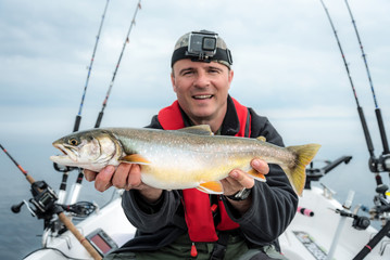 Happy angler with arctic char fishing trophy © Piotr Wawrzyniuk