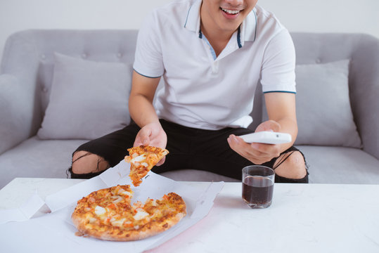 Man watch TV and eating pizza with soft drink. Close up. Sitting on sofa