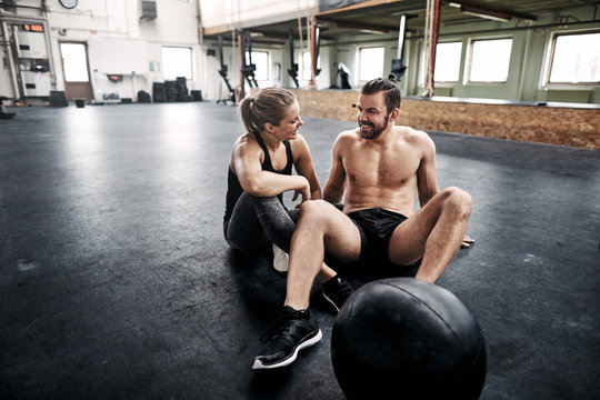 Fit people talking together on a gym floor after exercising