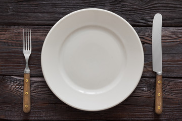 Plate, fork and knife on wooden background