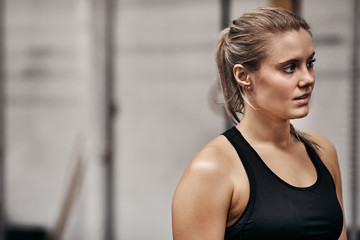 Fototapeta na wymiar Fit young woman looking focused while standing in a gym