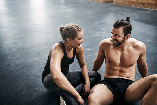 Fit young couple sitting together on a health club floor