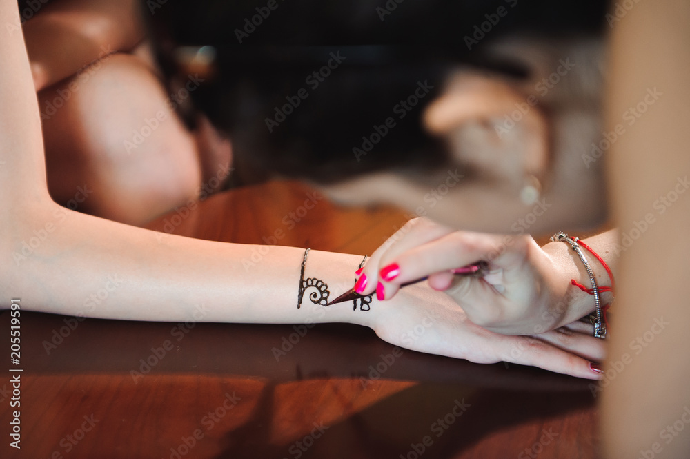 Wall mural artist applying henna tattoo on women hands. mehndi is traditional indian decorative art. close-up