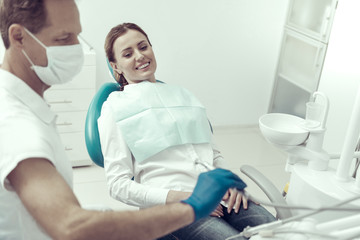 Very easy. Cheerful smiling young patient looking absolutely not worried while sitting in a dental chair with a dentist by her side