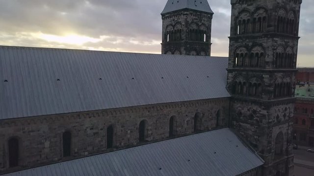 Lund Cathedral aerial drone shot. Flying up next to church building and towers, Lund city skyline at sunset