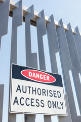 Warning sign against unauthorised access on a high steel fence.