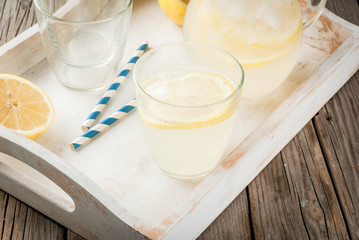 Classic sour and sweet homemade lemonade drink, summer cold iced beverage, rustic wooden background copy space in white tray